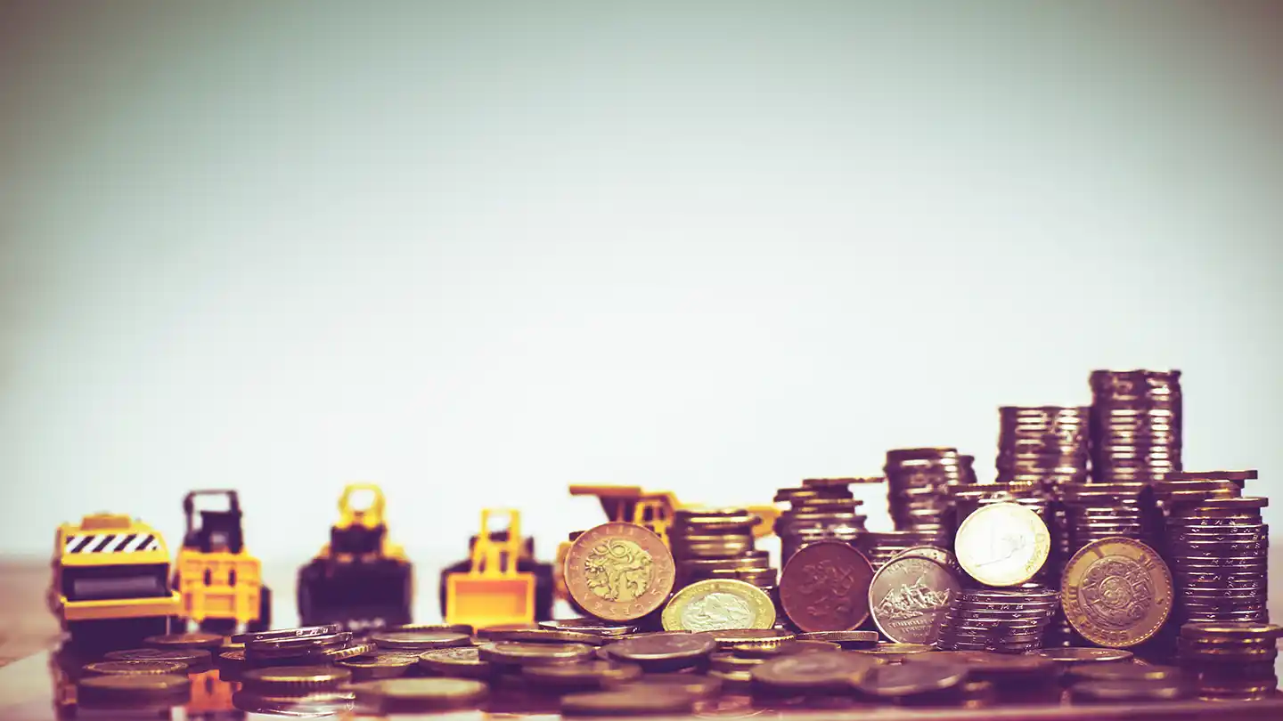 Stacks of coins with miniature heavy equipment, representing the cost comparison between rebuilt and new engines.